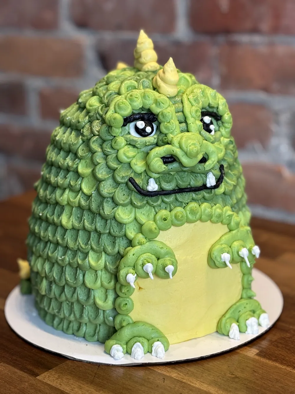 A green dinosaur cake covered in piped buttercream scales