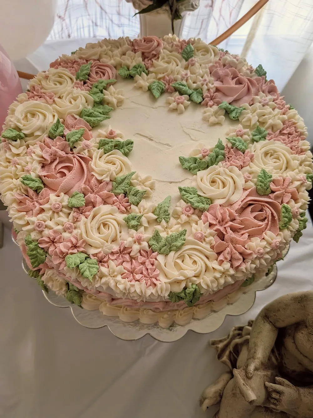 A round cake topped with piped pink and cream roses